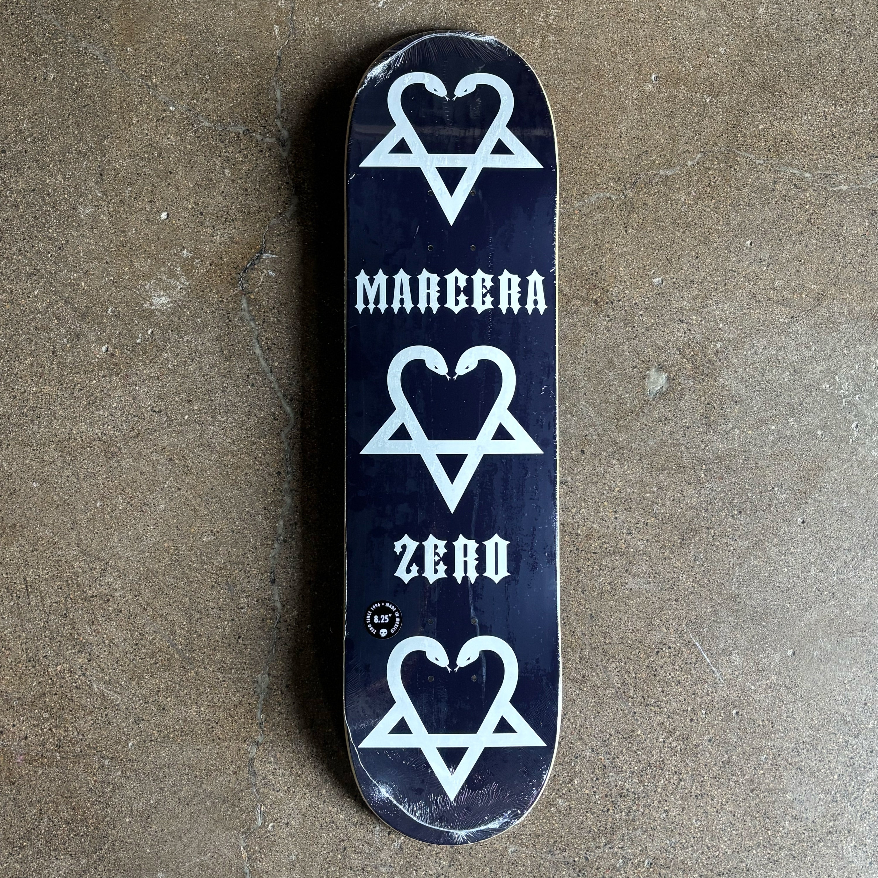 Black skateboard deck with white heart and triangle design, featuring 'Margera' and 'Zero' branding.